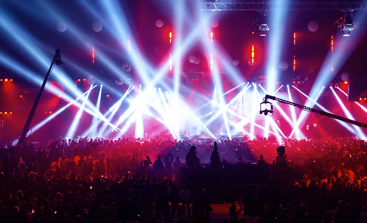 Koncert w hali: scena w ruchomych światłach, kamera na żurawiu nad publicznością